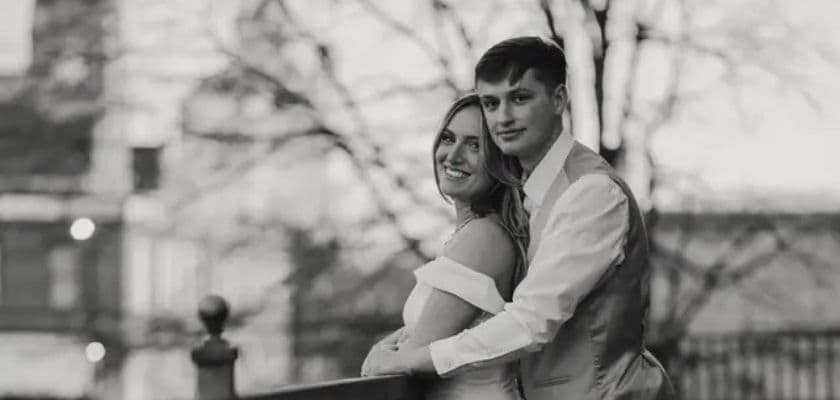A couple embraces happily on a balcony, captured in a black and white photograph.