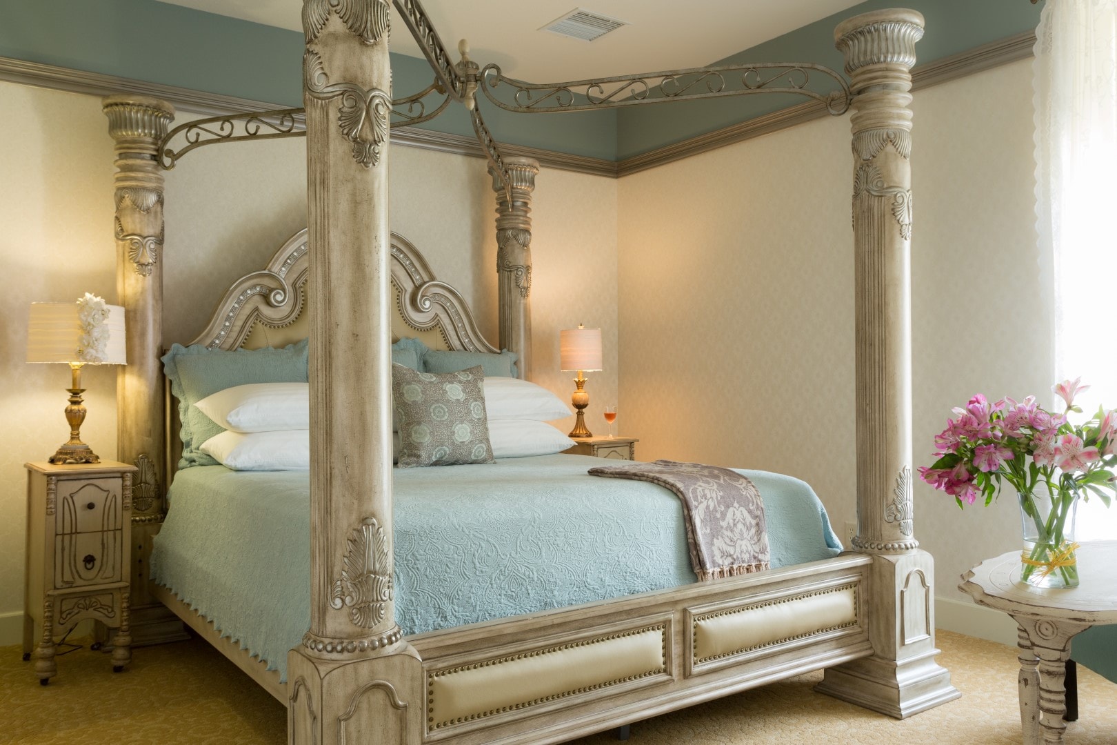 A beautifully decorated bedroom featuring a grand four-poster bed with elegant bedding and tasteful lighting.