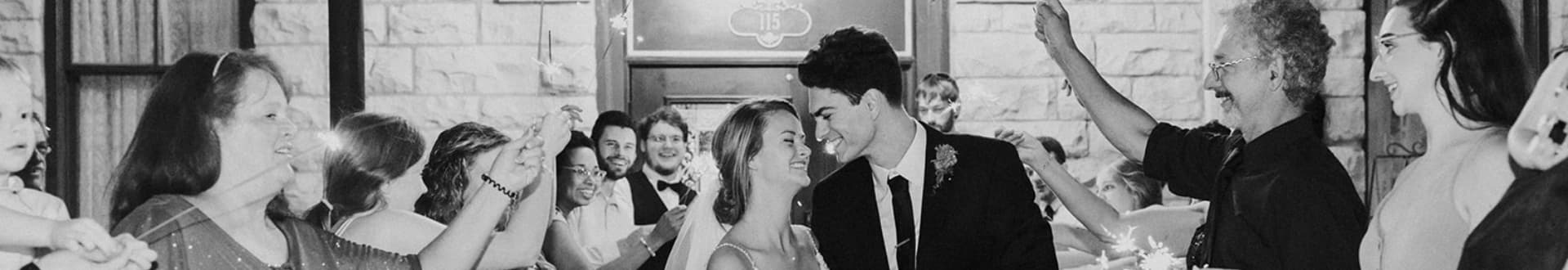 A couple is surrounded by guests celebrating at a joyful event.