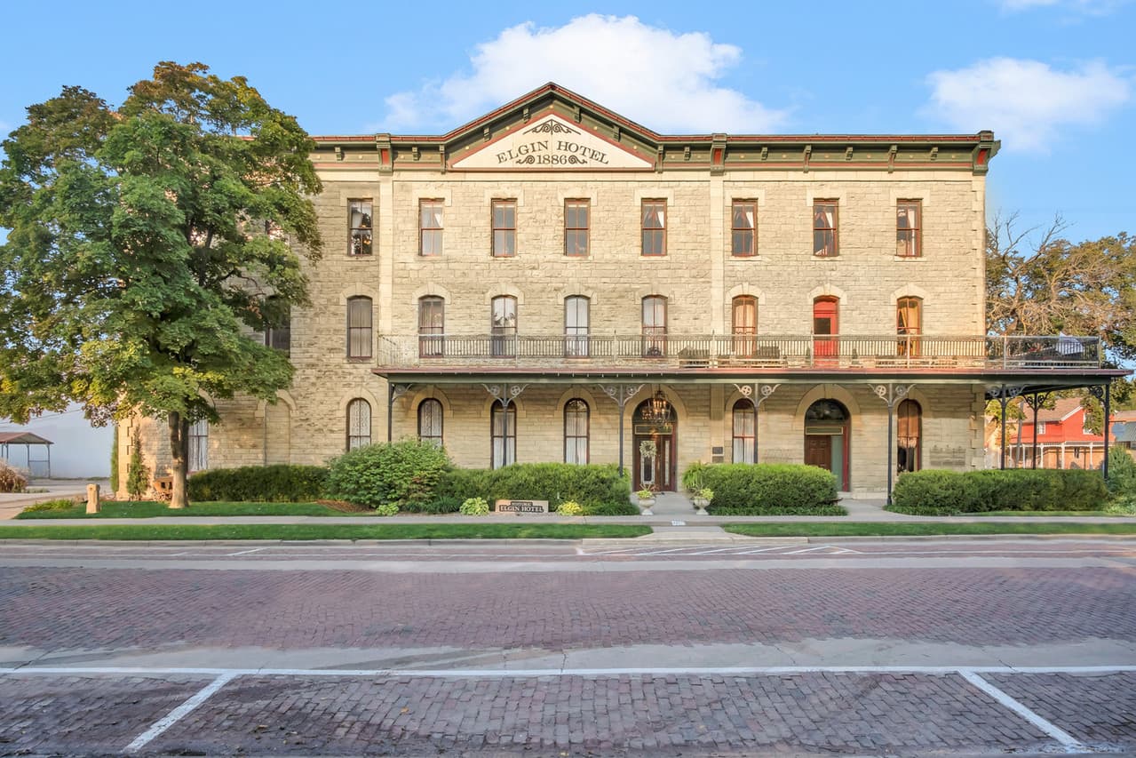 Front view of the historic Elgin Hotel, showcasing its stone facade and balconies.