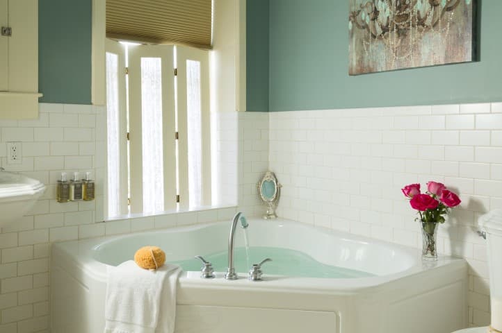 A serene bathroom featuring a jetted tub, fresh flowers, and soft lighting.