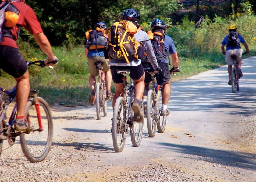 A group of mountain bikers riding along a gravel path. A group of mountain bikers riding along a gravel path.