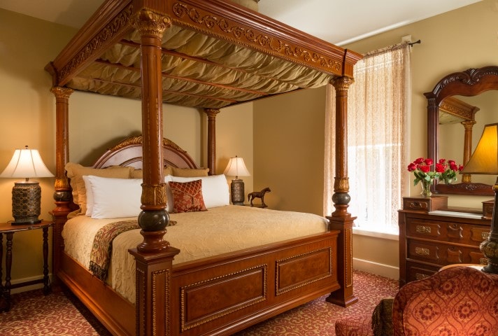 A beautifully designed bedroom featuring a four-poster bed, elegant furnishings, and soft lighting.