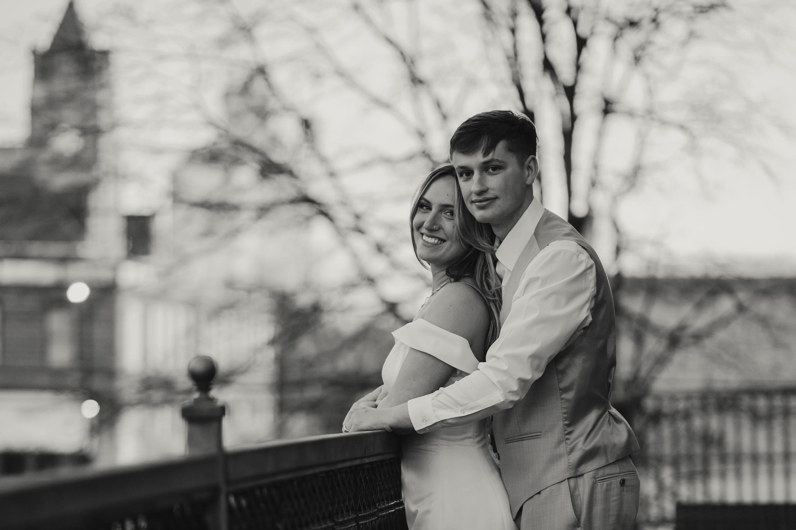 A happy couple embraces outdoors, smiling warmly at the camera.