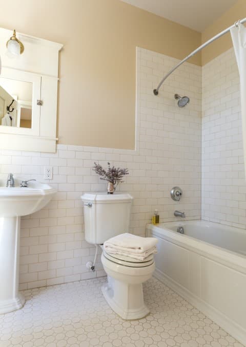 A clean, modern bathroom featuring a shower, bathtub, sink, and toilet with decorative towels.