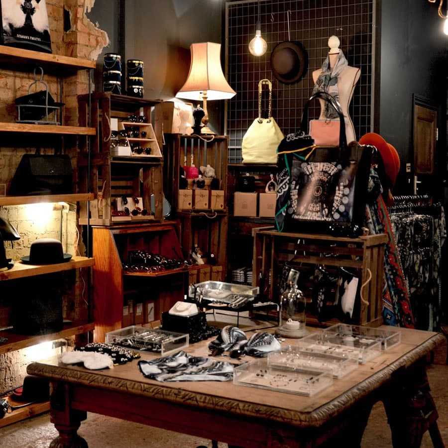 A cozy boutique showcasing accessories, jewelry, and bags on wooden shelves and tables.
