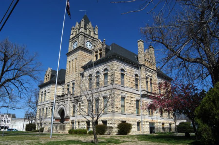 Historic stone courthouse with a clock tower against a clear blue sky.