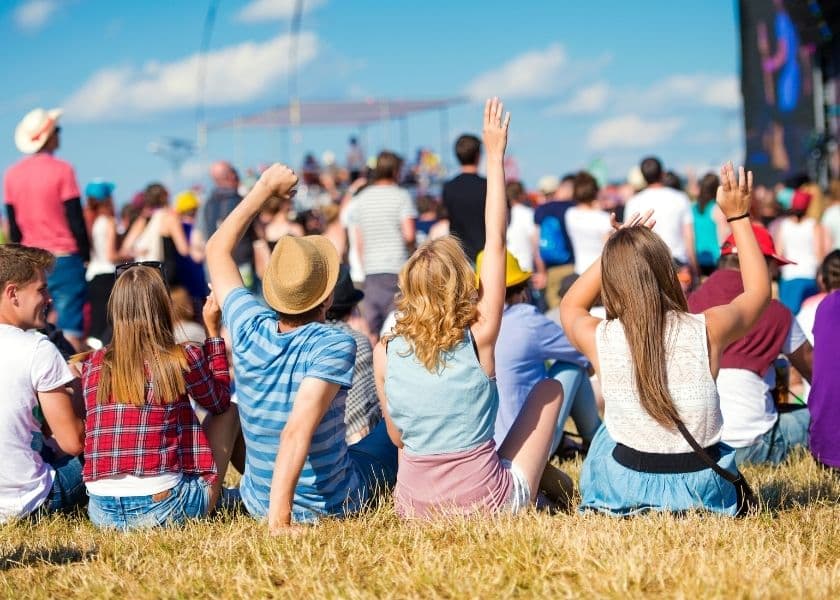 A group of people raise their hands in excitement at a festival. A group of people raise their hands in excitement at a festival.